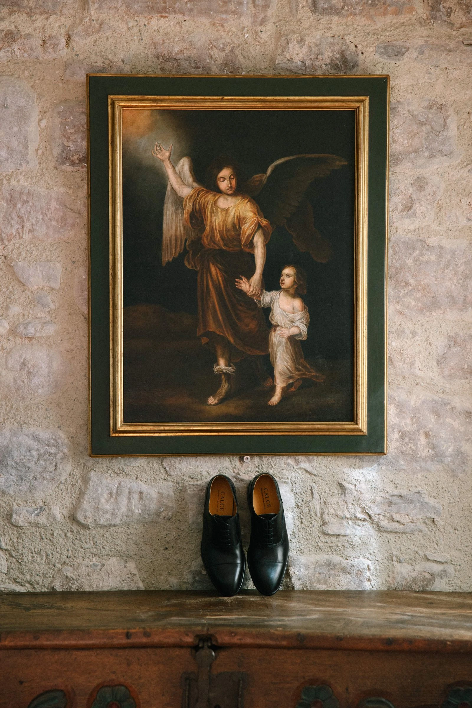 Zapatos del novio sobre una cómoda bajo un cuadro antiguo