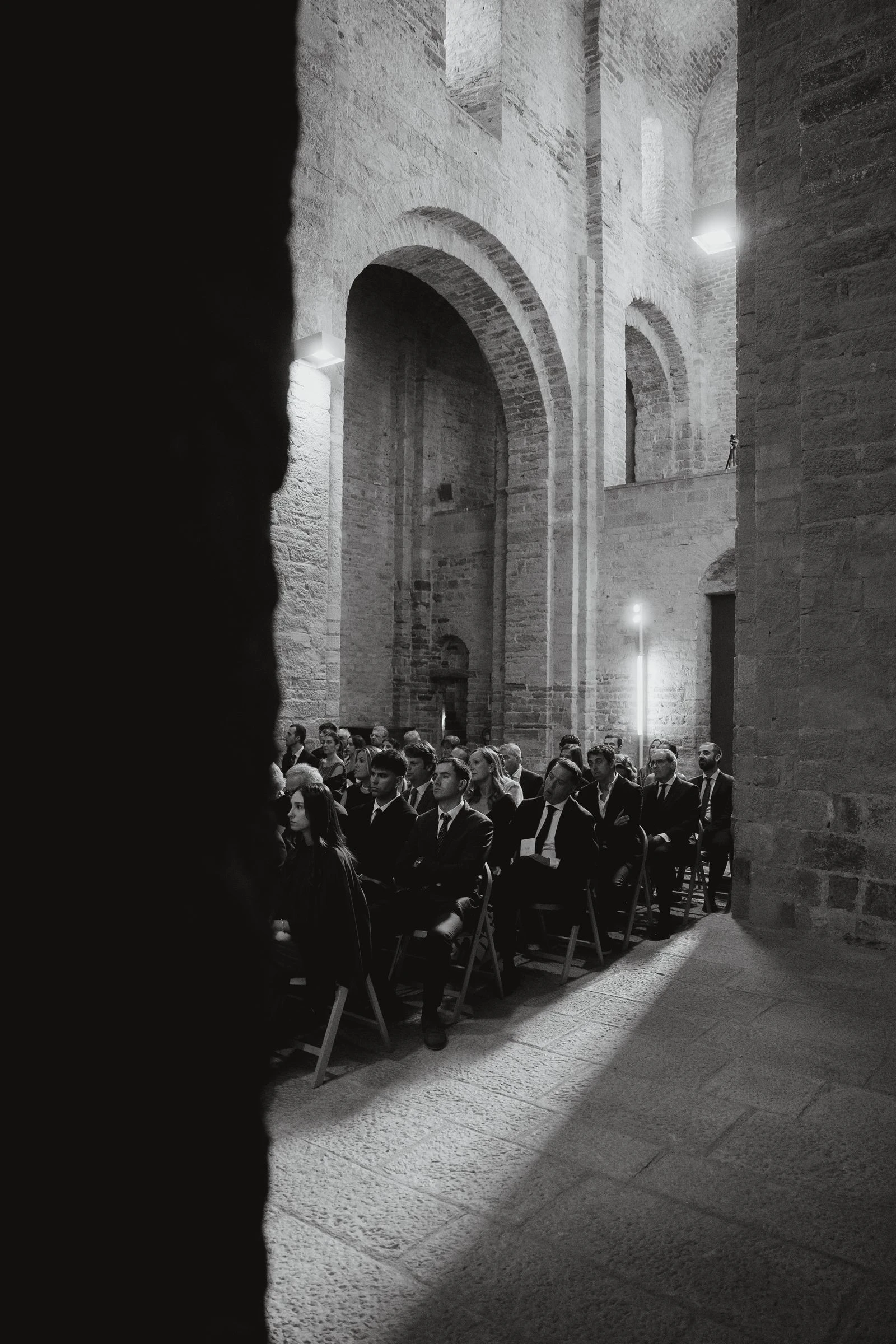 Haz de luz sobre los invitados durante la ceremonia, en blanco y negro