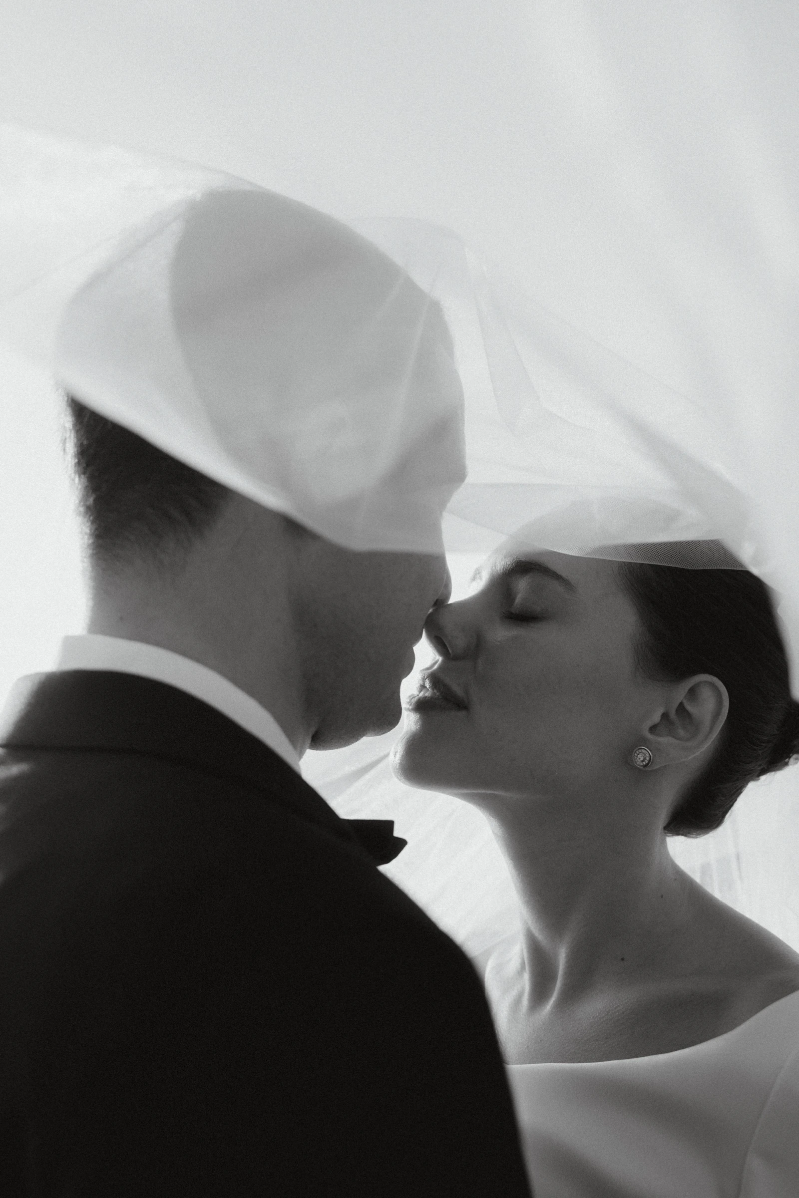 Novios besándose bajo el velo, en blanco y negro