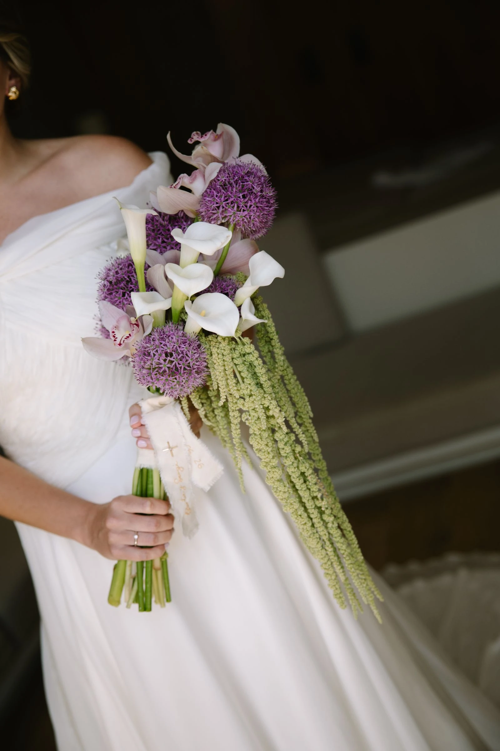 Ramo de calas y alliums morados sobre el vestido