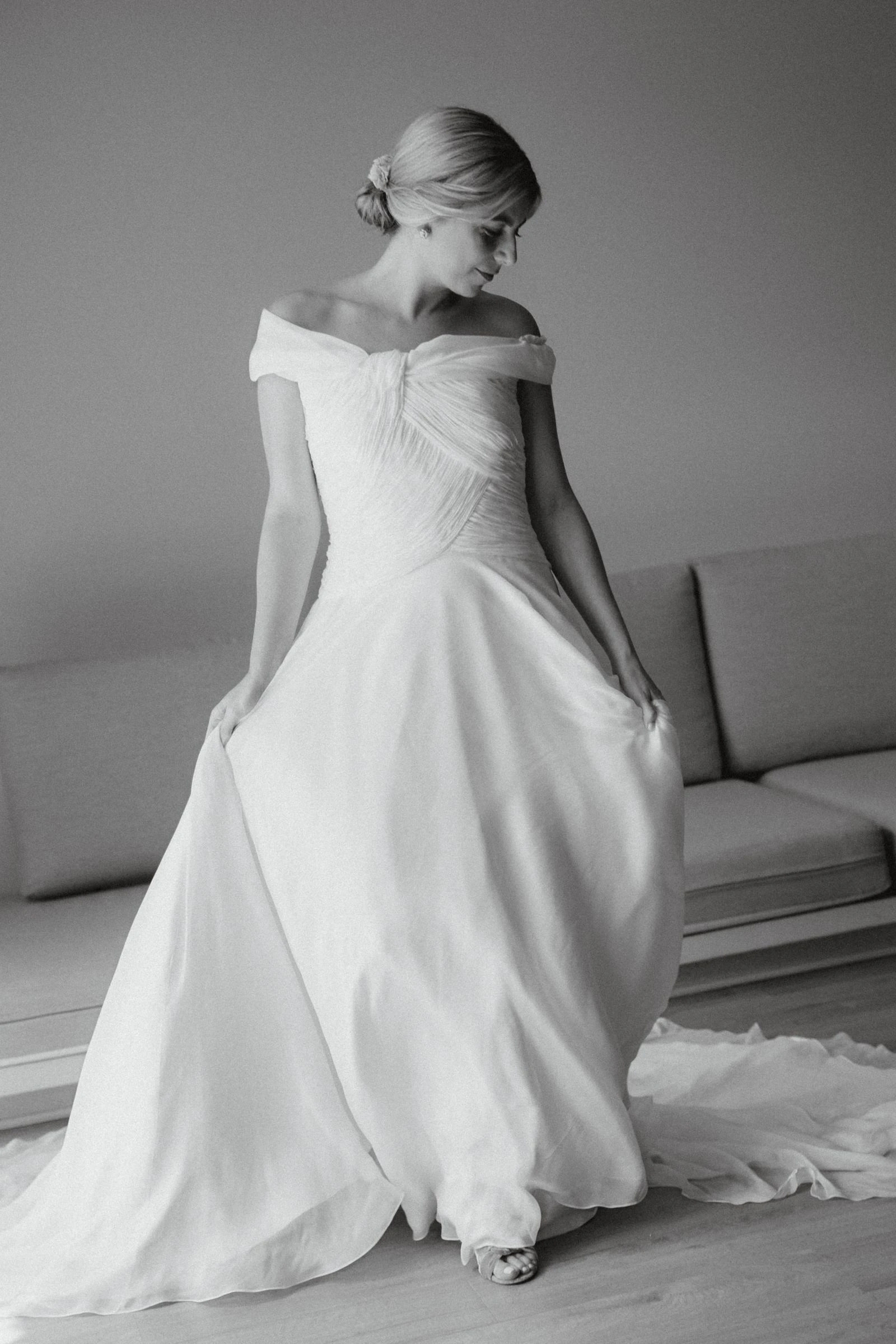 Novia de pie con vestido de escote barco, en blanco y negro