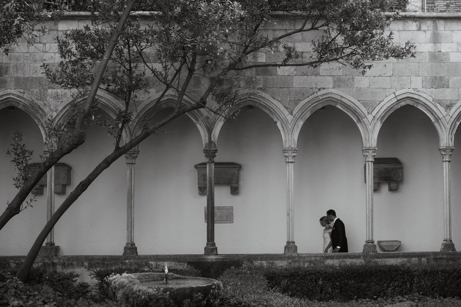 Novios abrazados bajo el claustro de un monasterio, en blanco y negro