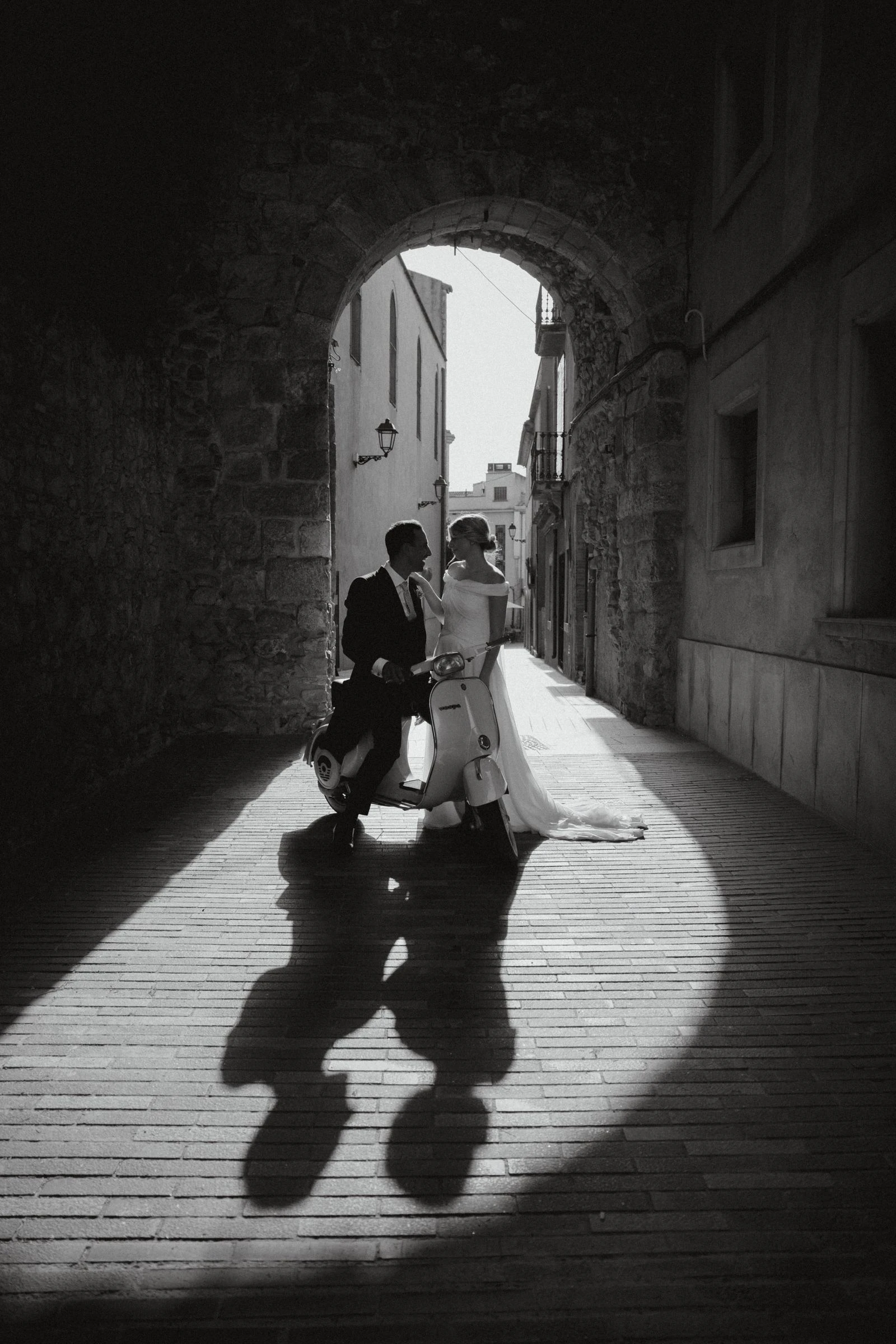 Novios y sus sombras en un callejón con luz, en blanco y negro
