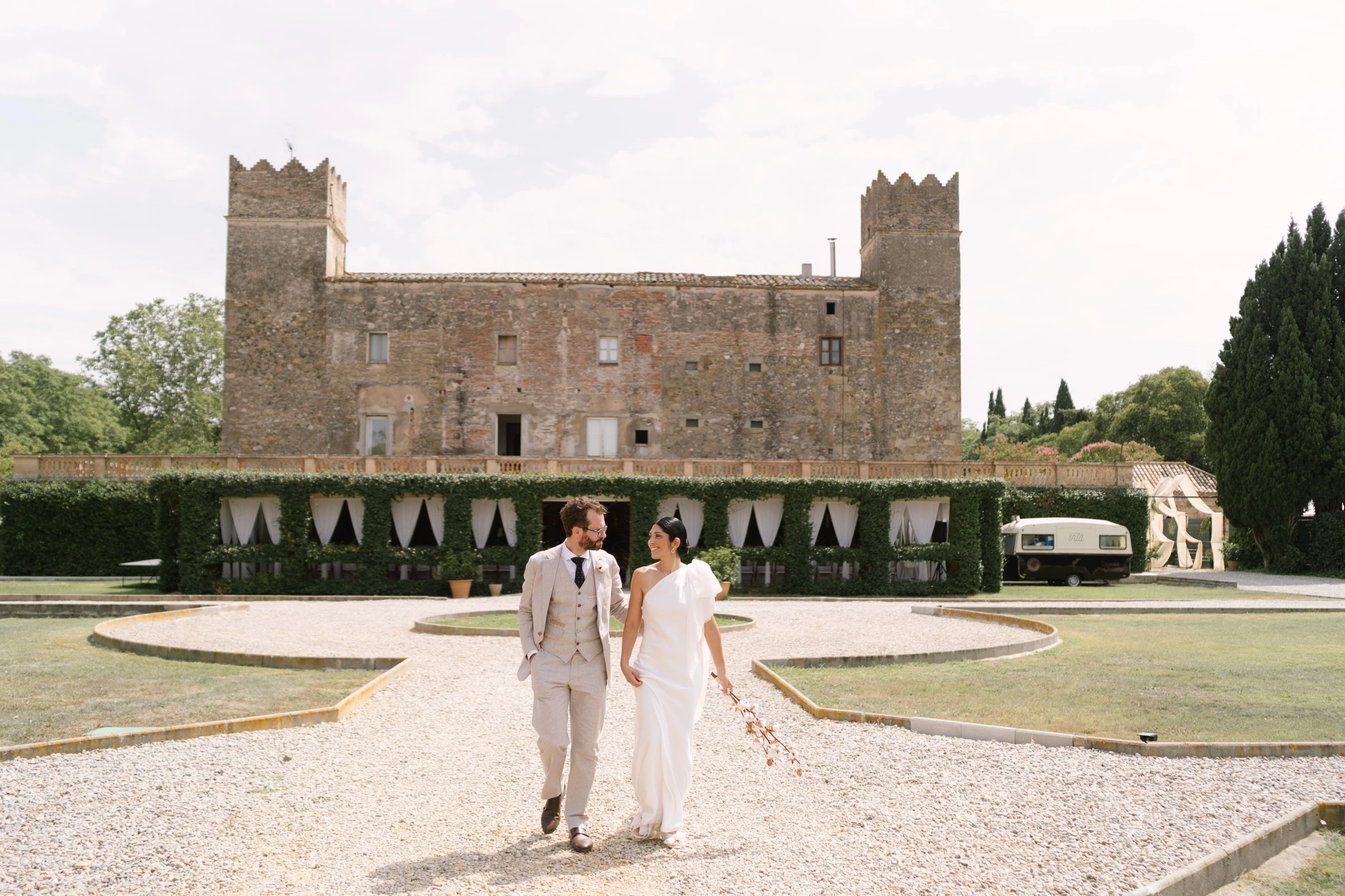 Novios paseando de la mano ante un castillo tras la ceremonia
