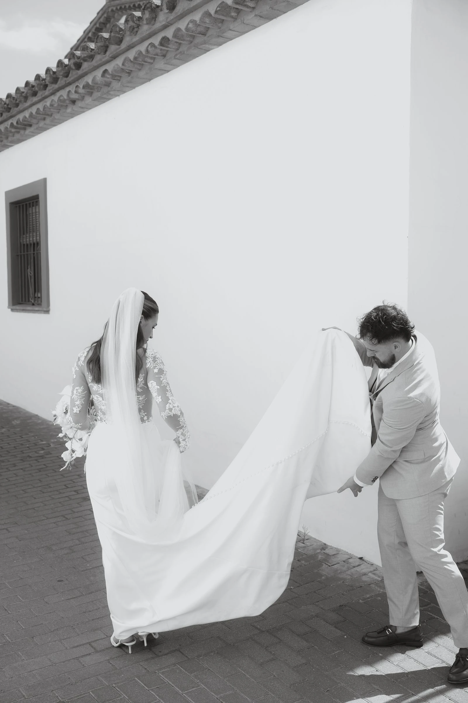 El novio recogiendo la cola del vestido, en blanco y negro