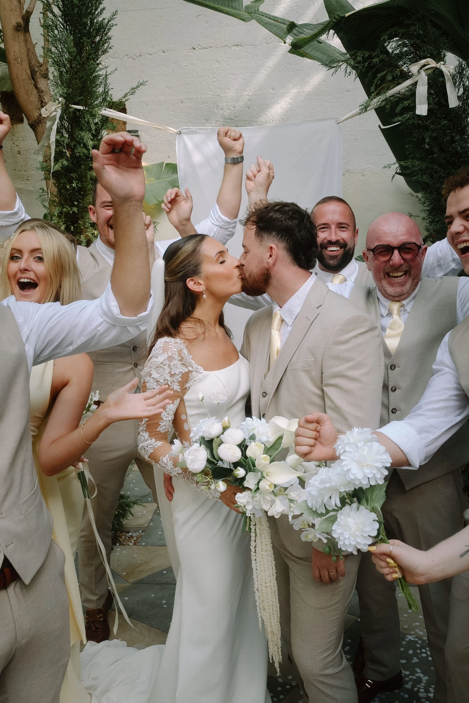 Novios besándose rodeados de amigos que celebran