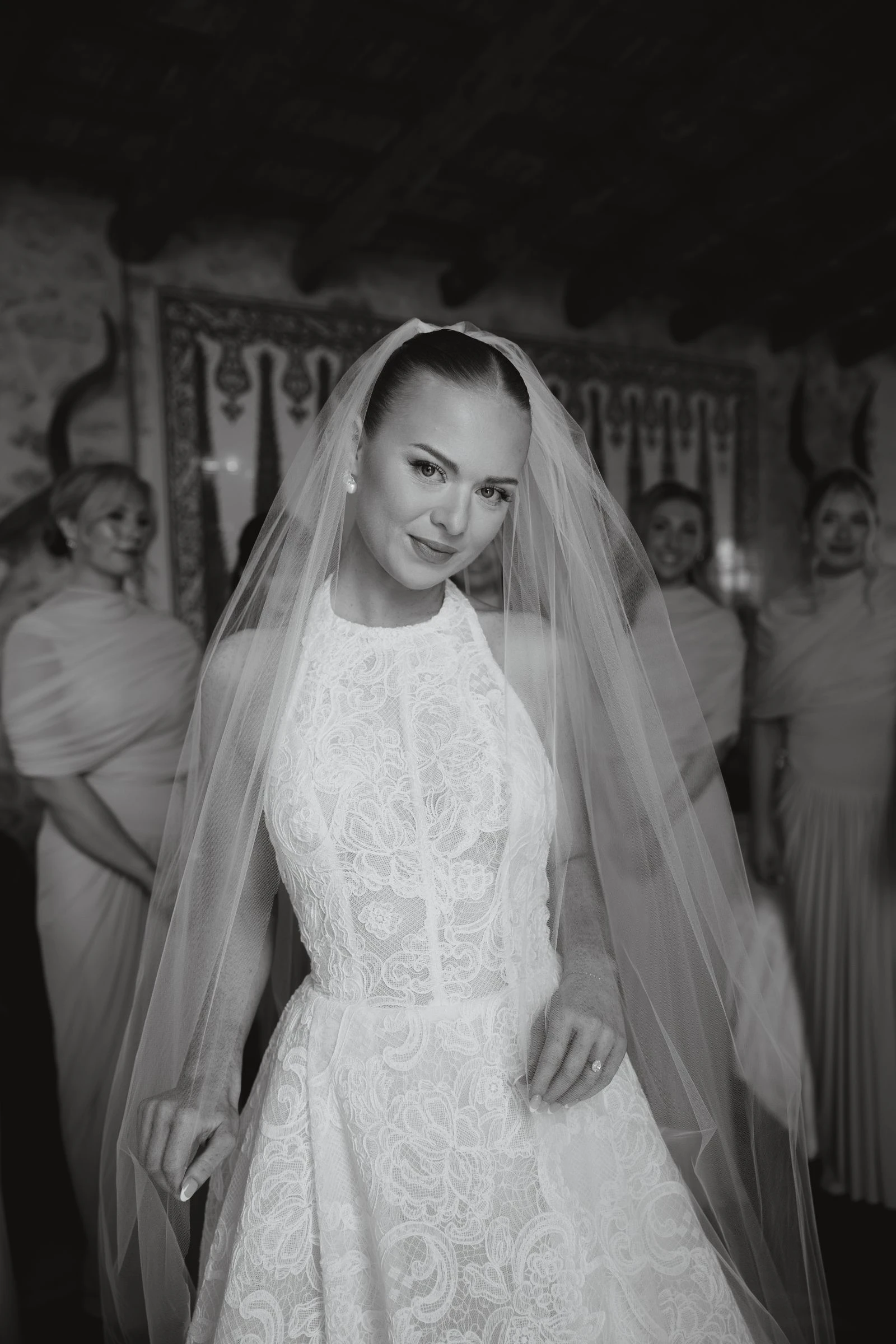 Retrato de la novia con el velo entre los invitados, en blanco y negro