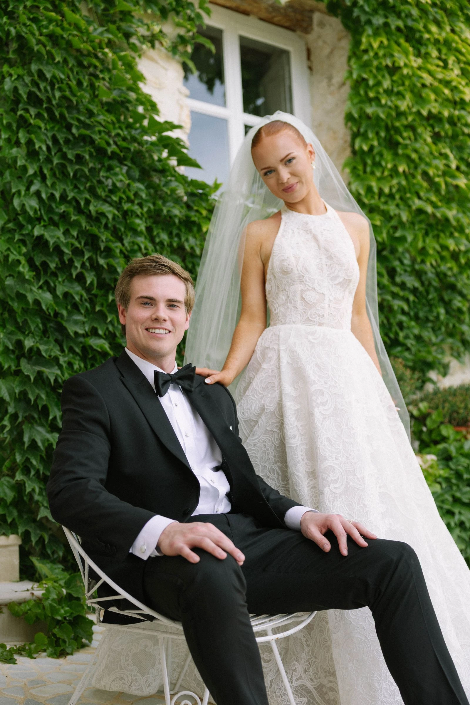 Retrato de los novios junto a una fachada cubierta de hiedra