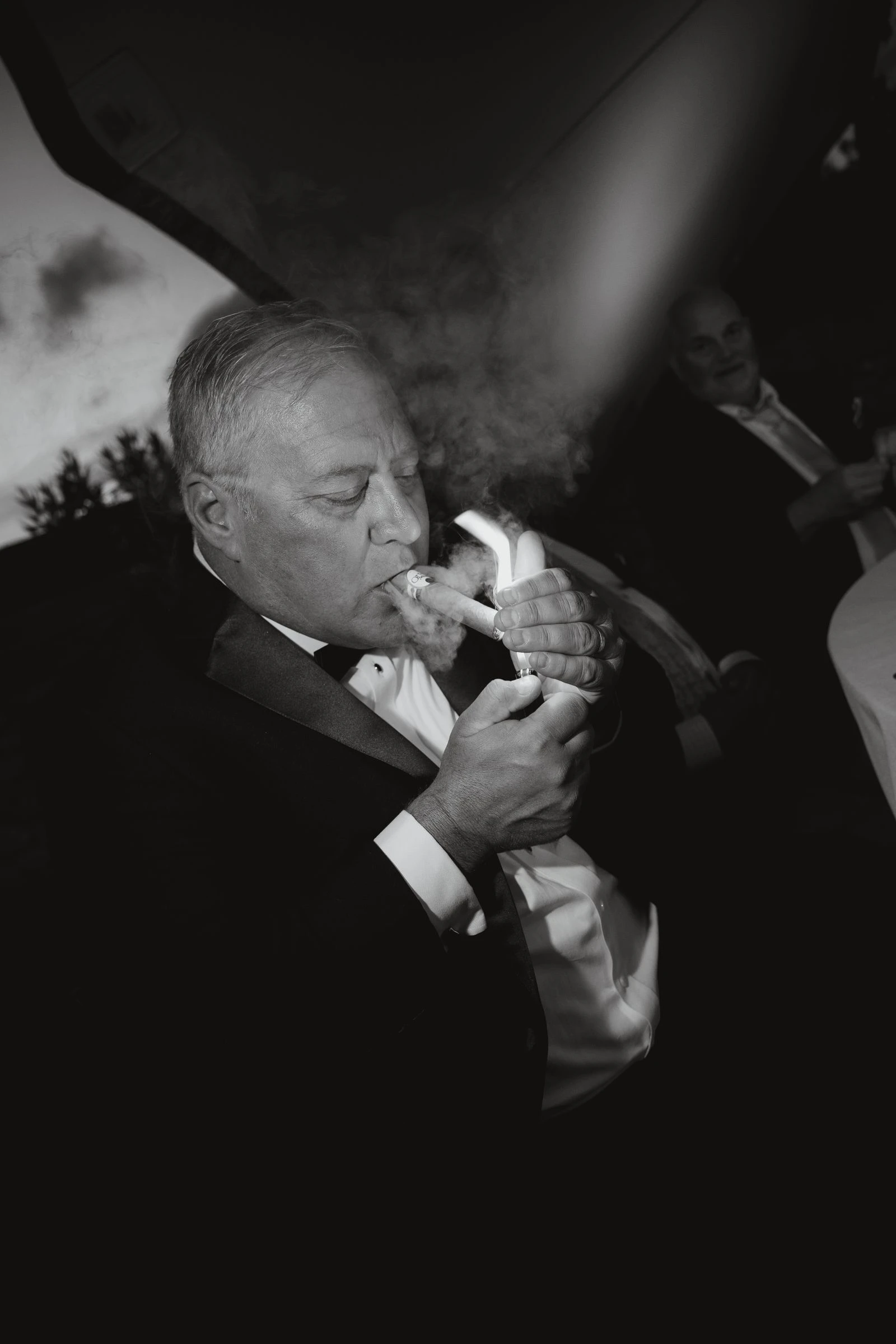 Un invitado encendiendo un puro durante la fiesta, en blanco y negro