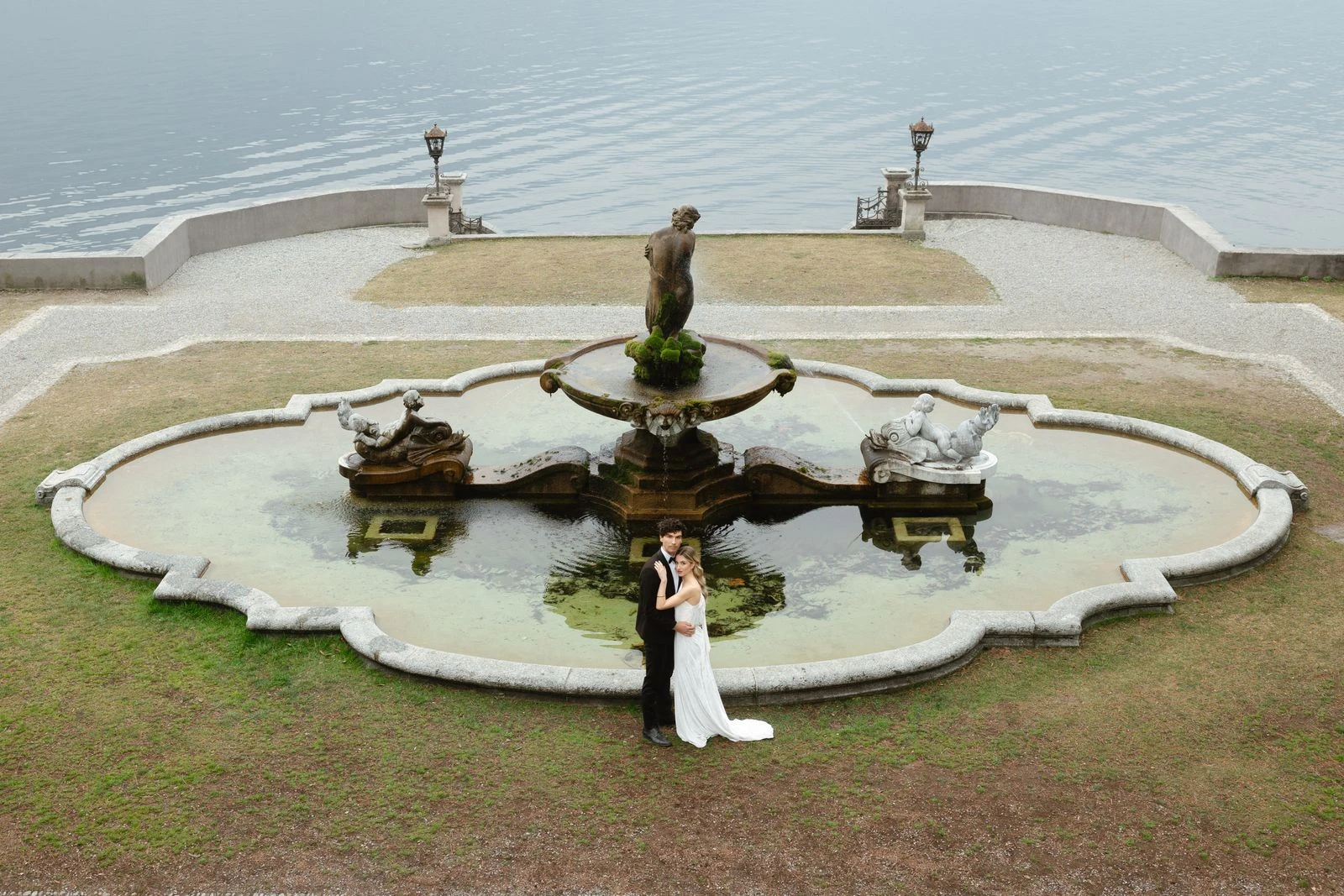 Novia junto a una fuente en un jardín frente al lago