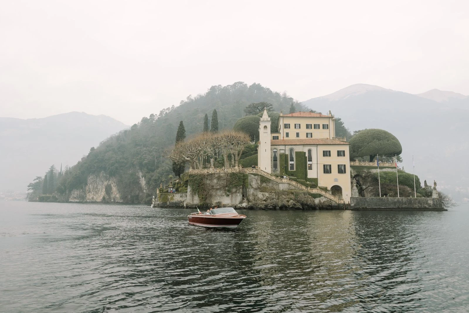 Isla con villa en el lago de Como entre la niebla