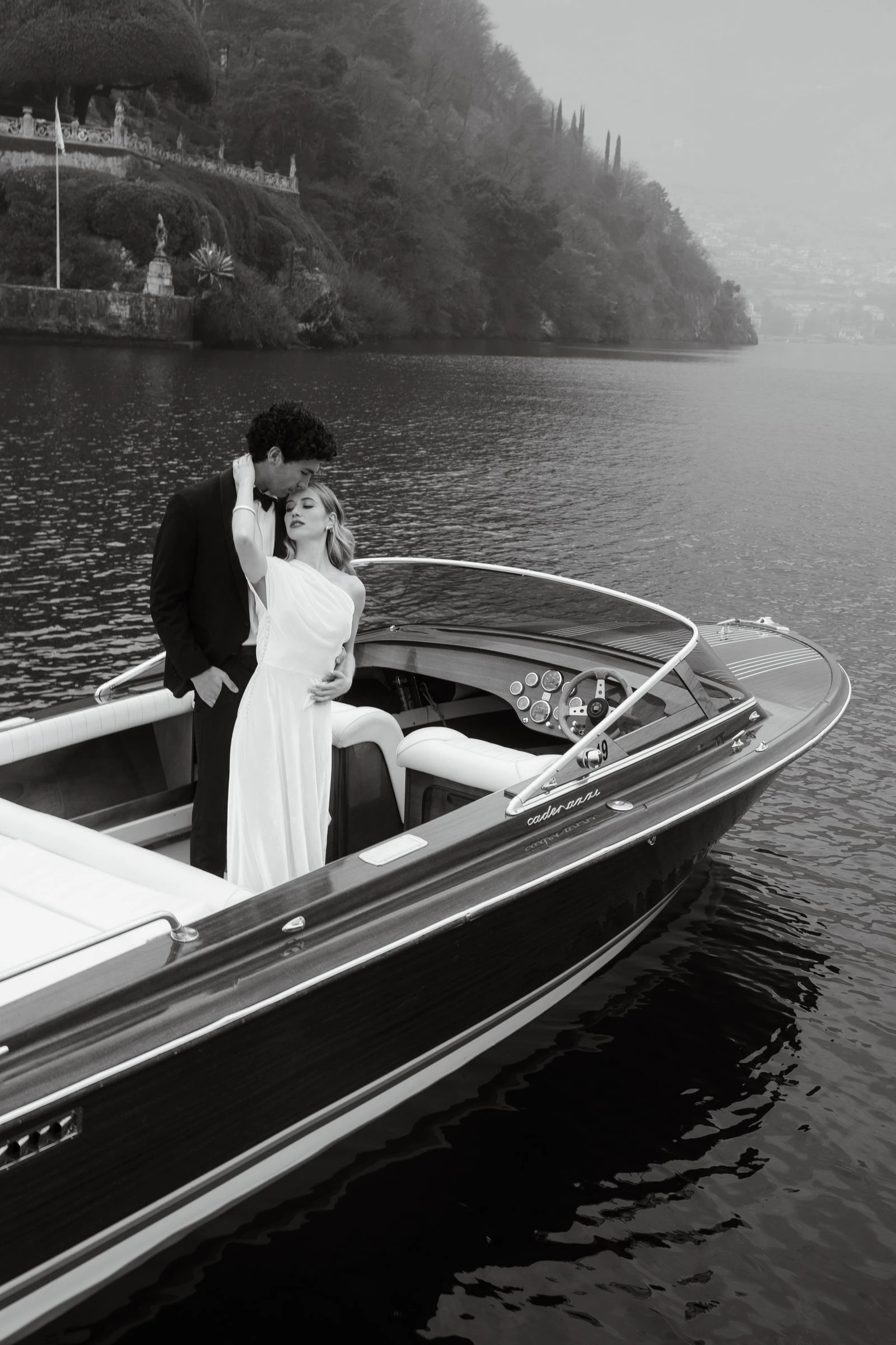 Novios abrazados en la lancha sobre el lago, en blanco y negro