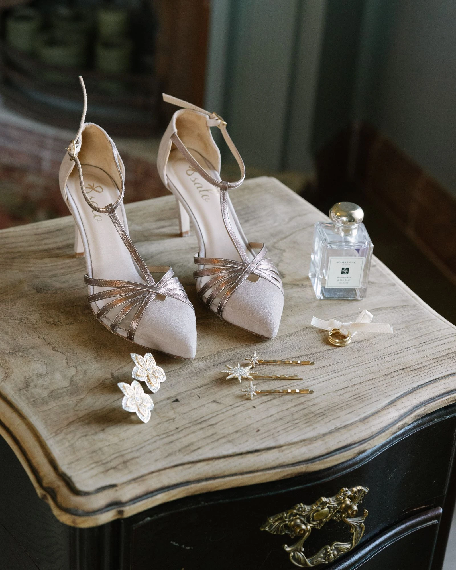 Zapatos de la novia, perfume y joyas sobre una mesa antigua