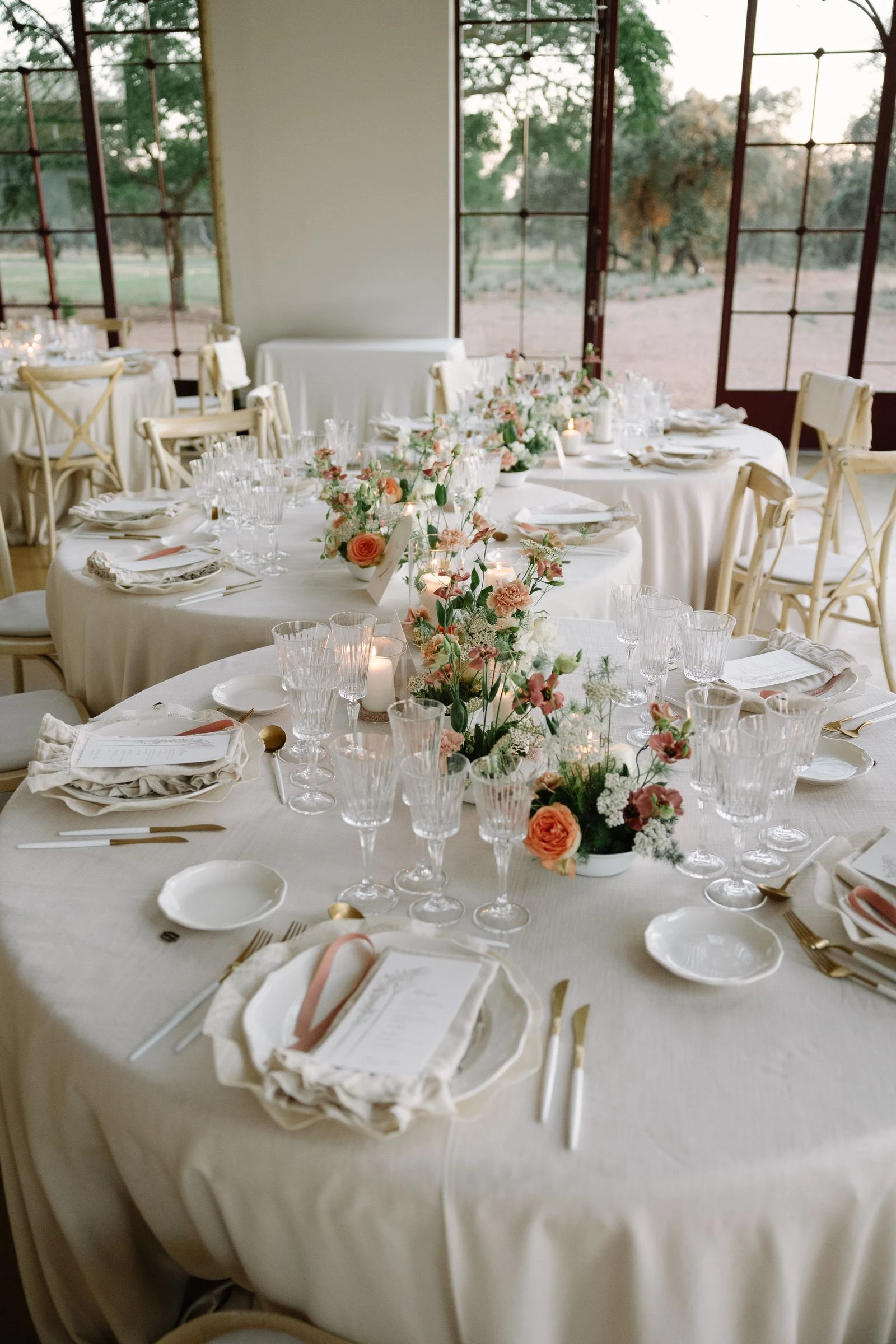 Mesas redondas del banquete con flores naranjas y cristalería