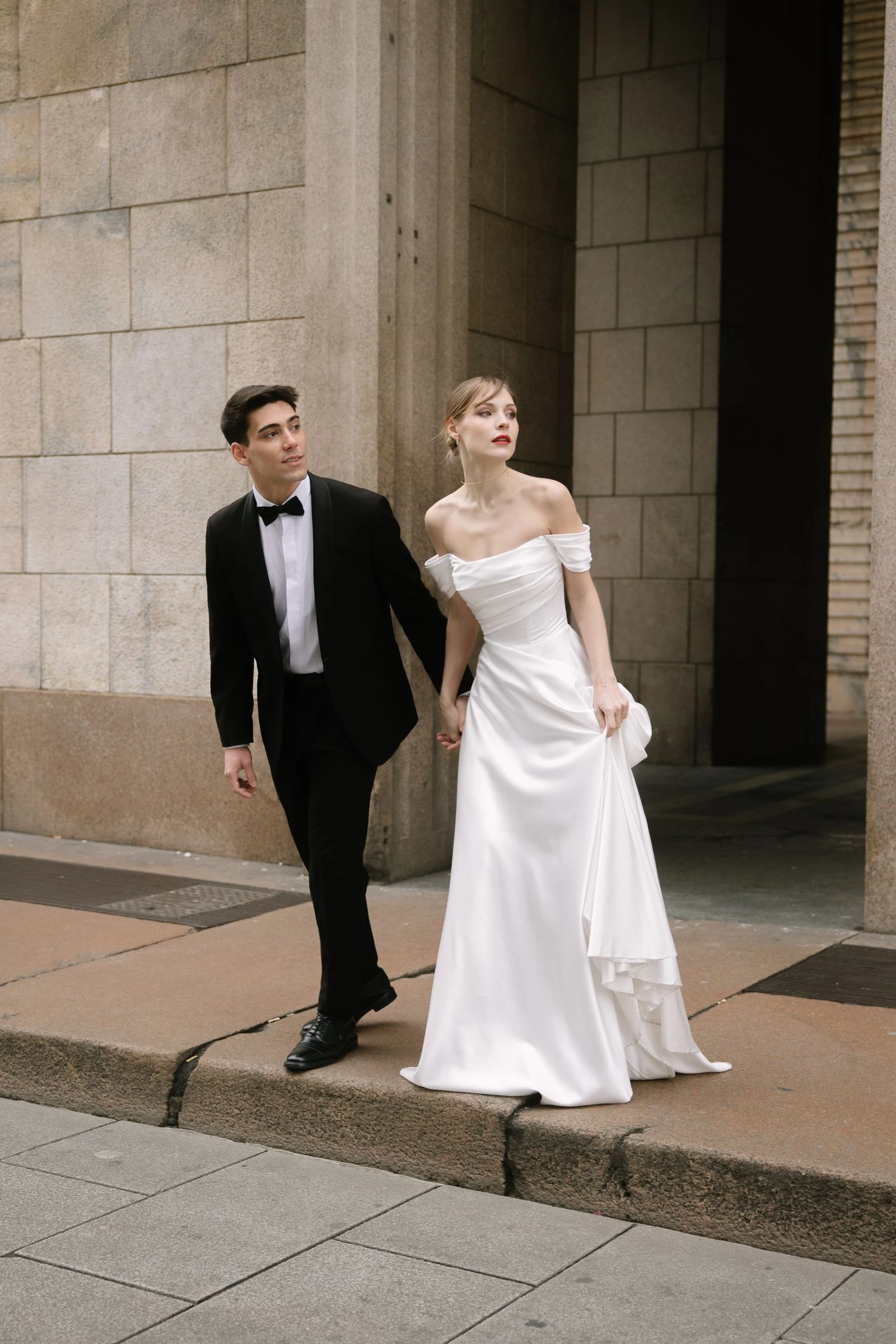 Novios caminando de la mano por una calle empedrada