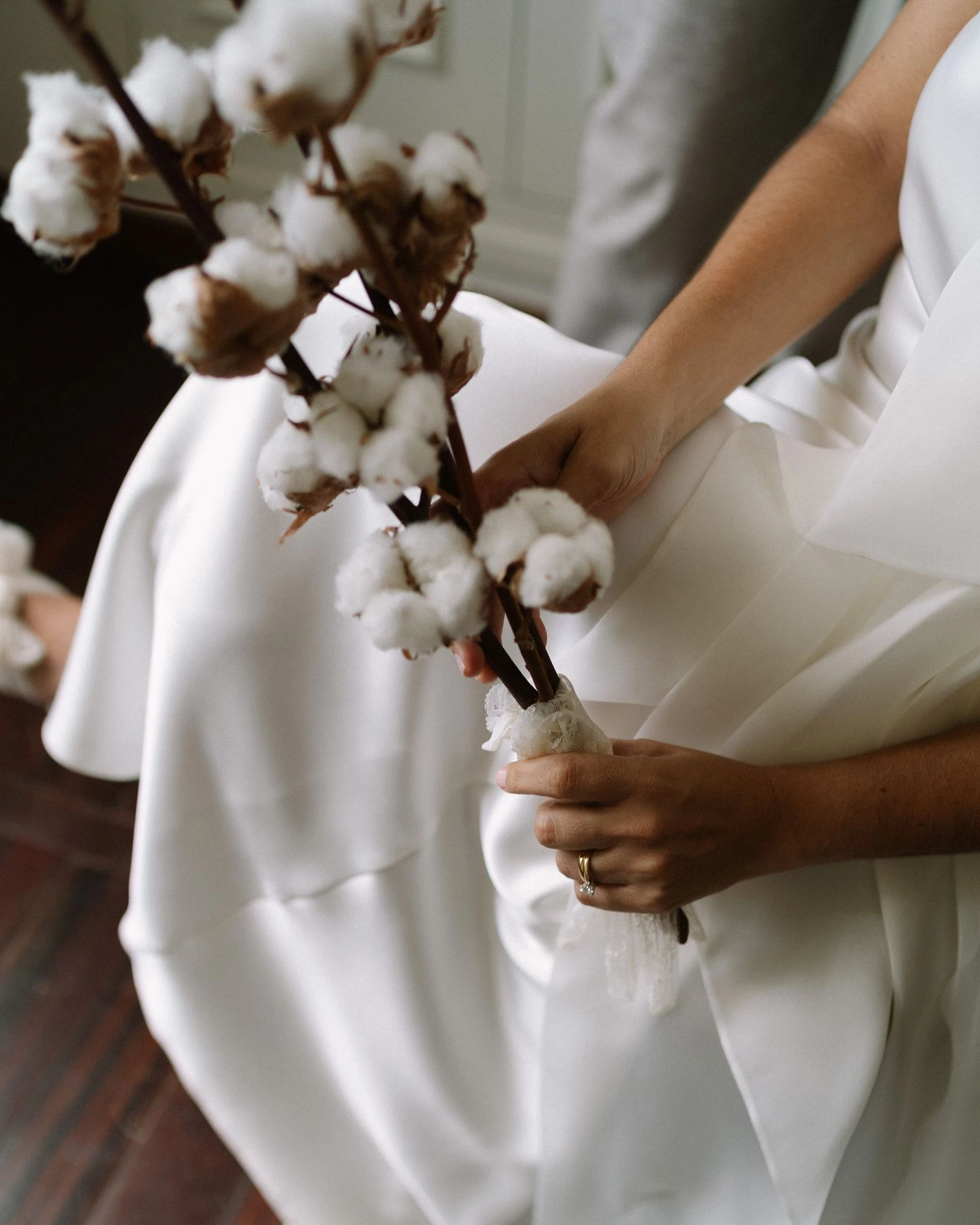 Manos de los novios sosteniendo ramas de algodón