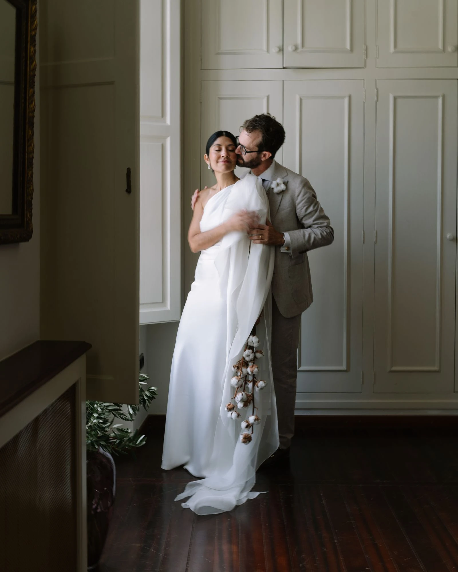 Novios abrazados en una sala interior con luz de ventana