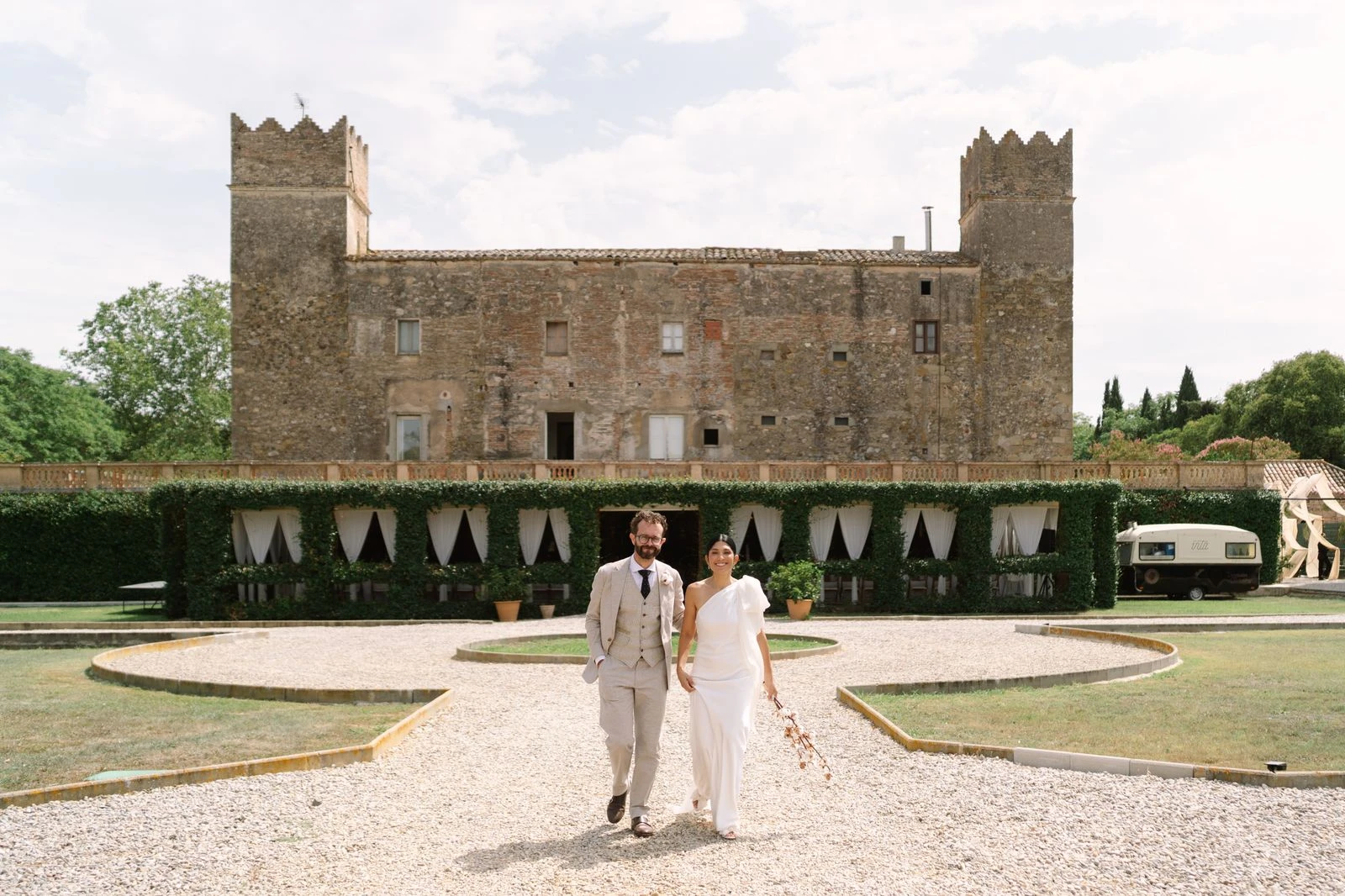 Novios caminando por el jardín frente al castillo