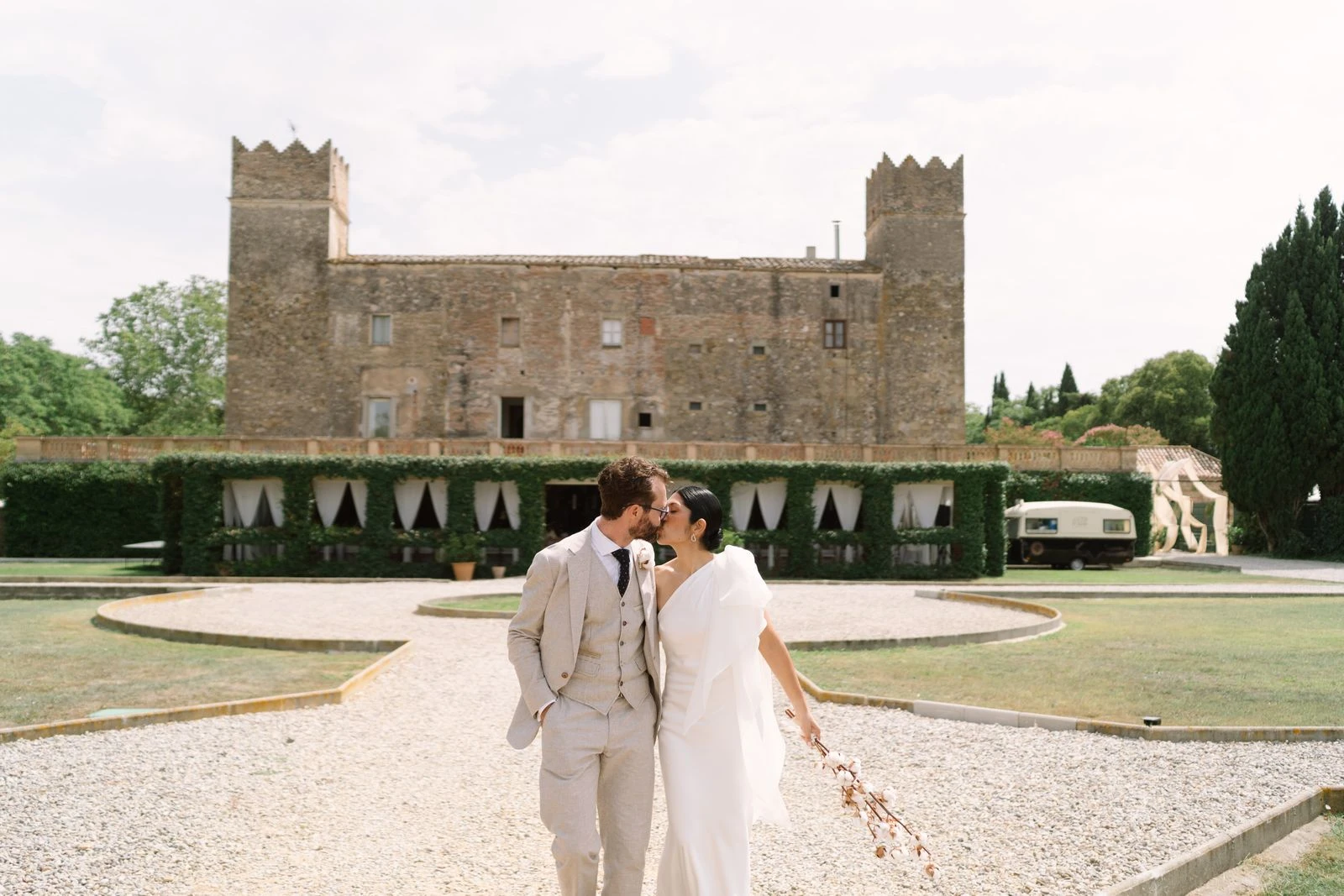 Novios besándose frente a un castillo, al fondo del jardín