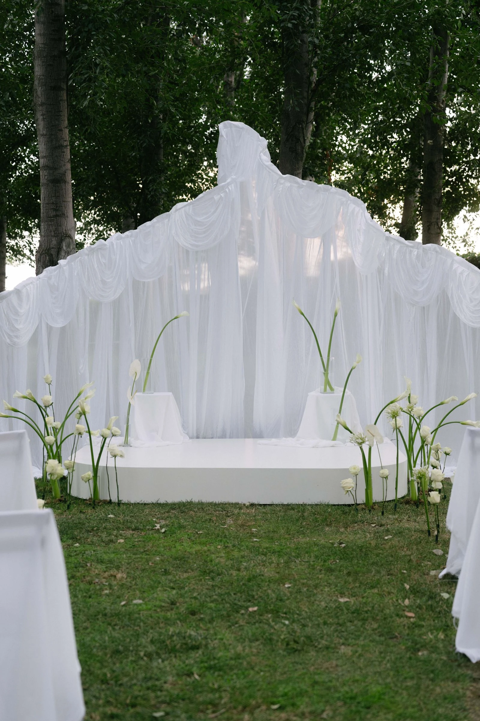 Altar de la ceremonia con telas blancas en el jardín