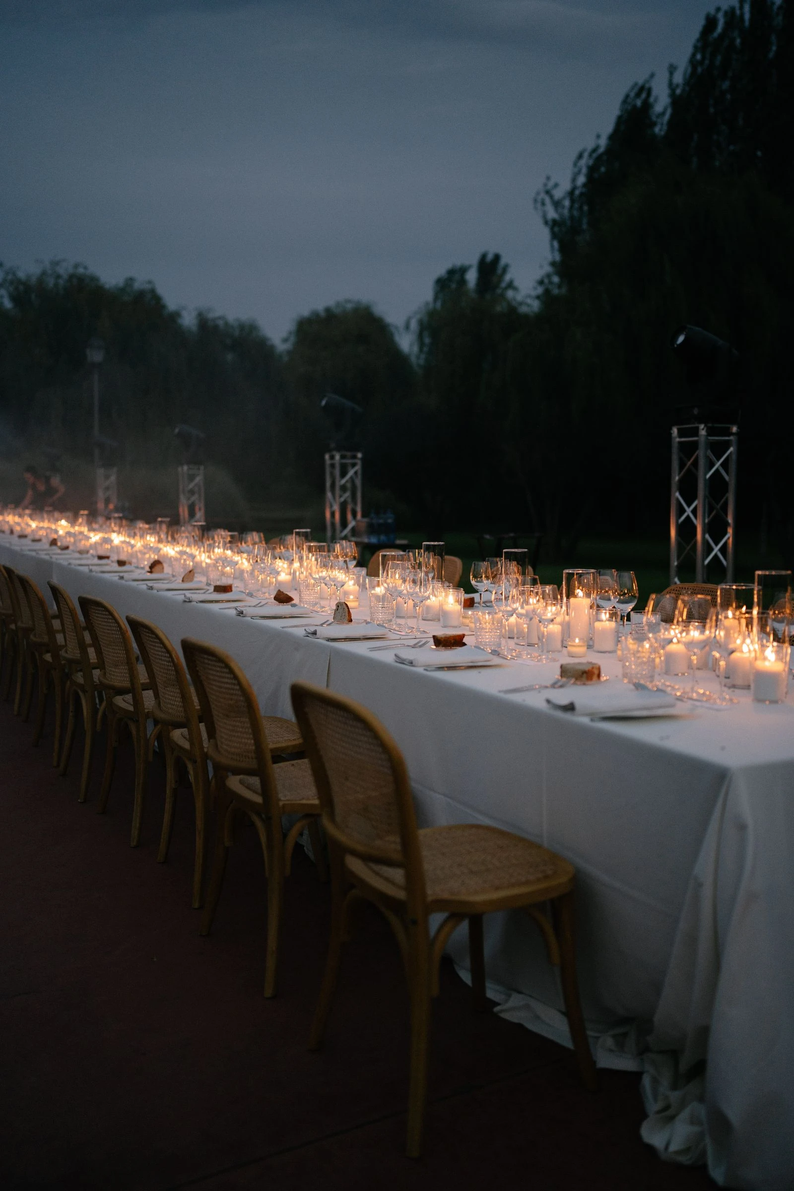 Mesa larga iluminada con velas al anochecer