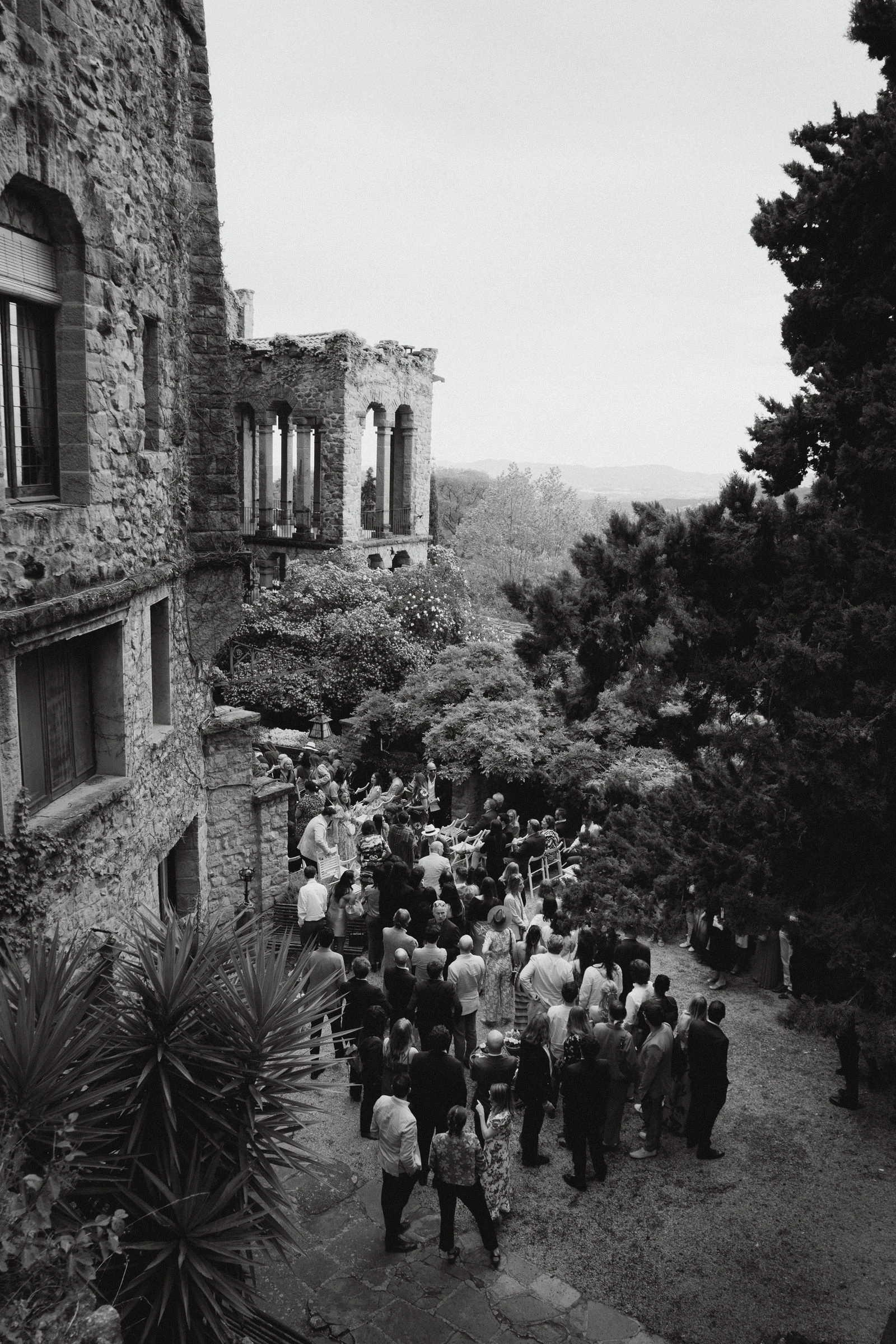 Invitados llegando a la ceremonia junto al castillo, en blanco y negro