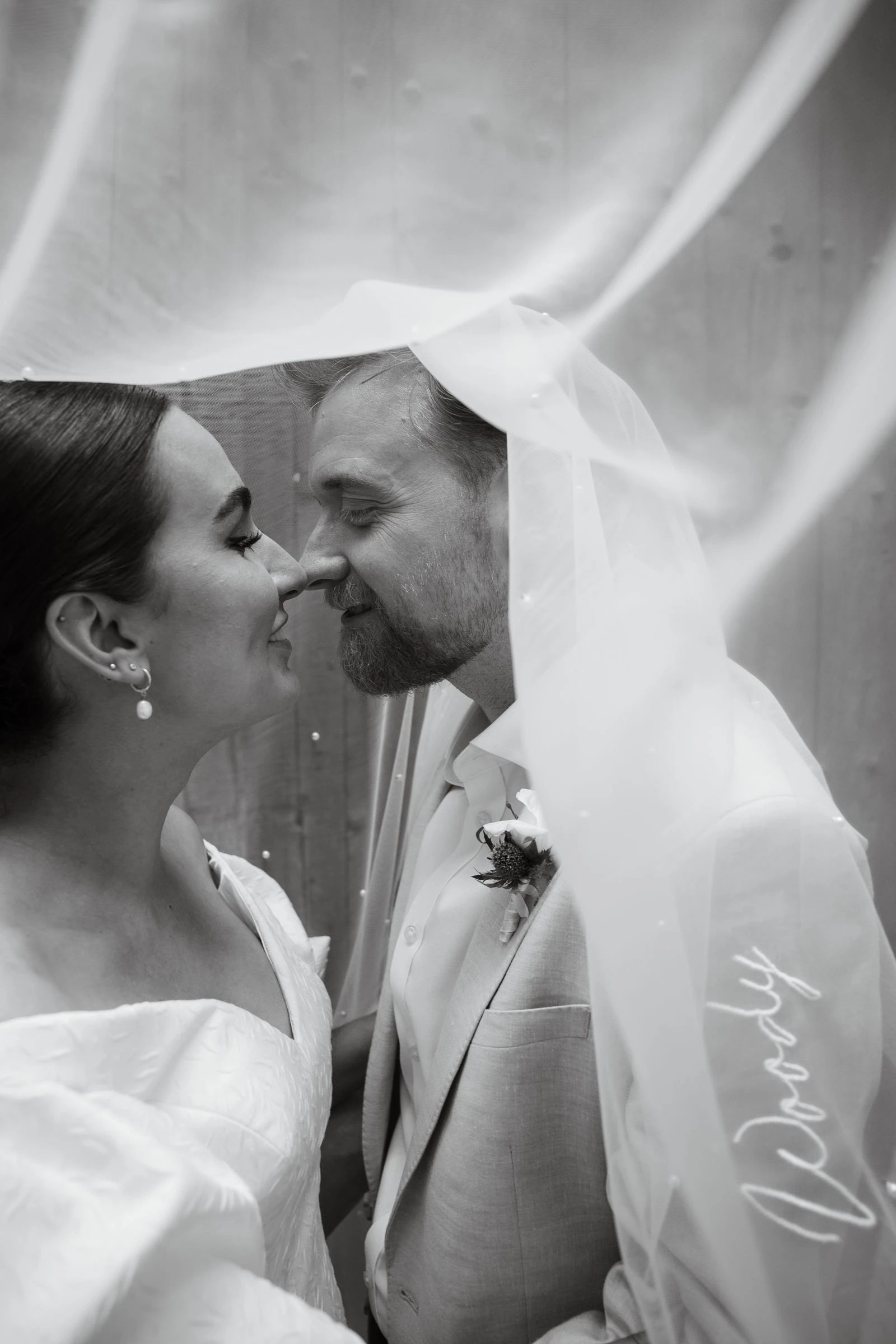 Novios besándose bajo el velo, en blanco y negro