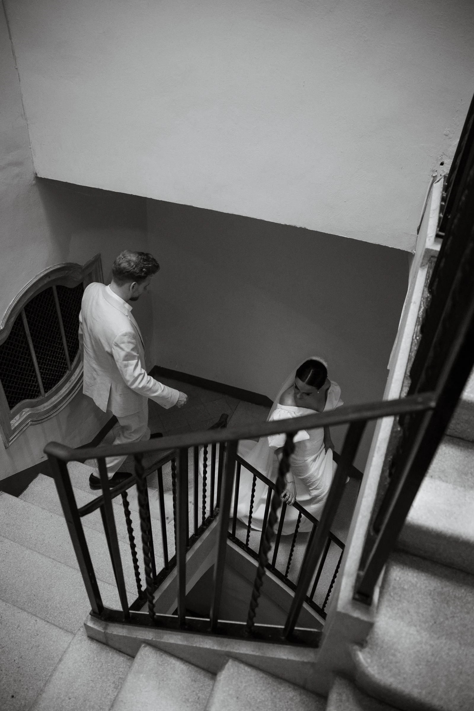 Los novios bajando una escalera vistos desde arriba, en blanco y negro